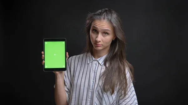 Closeup shoot of young pretty caucasian female texting on the tablet and showing green screen to camera with isolated background — Stock Photo, Image