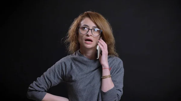 Primer plano retrato de mujer pelirroja extravagante de mediana edad en gafas teniendo una conversación casual en el teléfono delante de la cámara —  Fotos de Stock