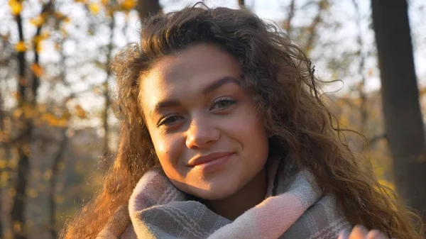 Retrato de menina caucasiana de cabelos cacheados bonita sorrindo para a câmera no parque outonal . — Fotografia de Stock