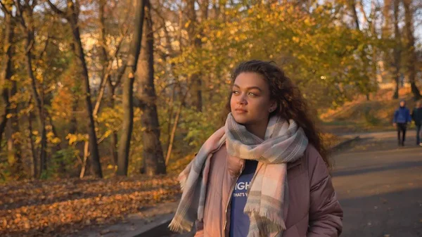 Retrato de hermosa chica caucásica de pelo rizado caminando en el parque otoñal y observando la belleza . — Foto de Stock