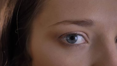 Yakın çekim yarı-portre sevimli genç esmer kadının içine kamera siyah arka plan üzerinde dikkatle izliyor.