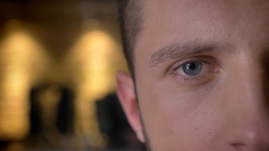 Closeup yarı-yüzü açık ateş yetişkin beyaz erkek göz kameraya kapalı ile iç arka planı arıyorum.