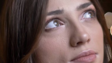 Yakın çekim göz-portresi güzel beyaz esmer kız yukarı sersem olarak izlerken ışıkları arka plan bulanık.
