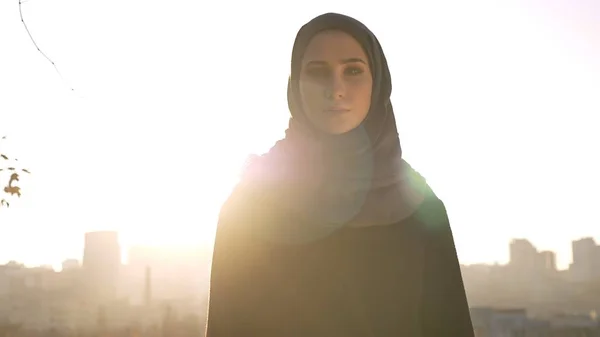 Gros plan de la jeune silhouette féminine séduisante en hijab regardant directement la caméra avec la ville urbaine en arrière-plan — Photo