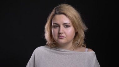Konsantre sarışın kısa saçlı kilolu işkadını cidden içine kamera siyah arka plan üzerinde izliyor..