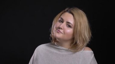 Orta yaşlı kısa saçlı kilolu işkadını kamera siyah arka plan üzerine flört gülümseme ile içine izlerken.