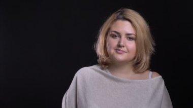 Siyah arka plan üzerine mütevazı gülümseme ile kamera içine orta yaşlı sarışın kısa saçlı kilolu işkadını saatler.