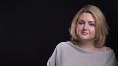 Kamera siyah arka plan üzerinde sakin bir şekilde içine orta yaşlı sarışın kısa saçlı kilolu işkadını saatler.