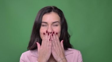 Genç esmer iş kadını pembe ceket bir öpücük mutlu yeşil renkli kamera içine üfleme..