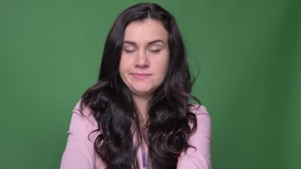 Portret van ernstige brunette zakenvrouw in roze jasje draait hoofd negatief te ontkennen of oneens op groene achtergrond. — Stockvideo