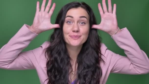 Portrait de femme d'affaires brune en veste rose faisant des visages drôles dans la caméra sur fond vert . — Video