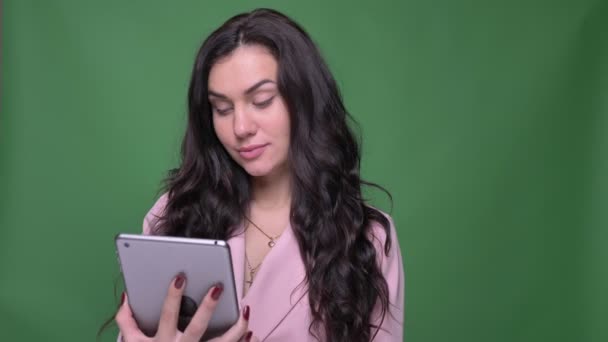 Брюнетка бізнес-леді в рожевій куртці демонструє синій екран планшета, щоб показати програму на зеленому фоні . — стокове відео