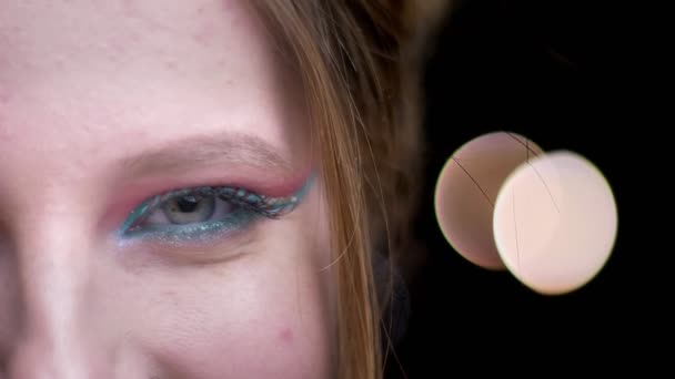 Close-up half-portrait of beautiful caucasian blonde girl with bright colorful make-up on blurred lights background. — Stock Video