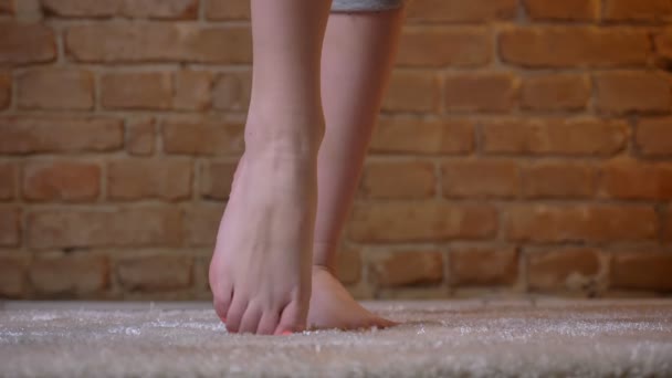 Gros plan de jambes féminines dansant et sautant sur un tapis à fourrure sur fond de mur de poulet . — Video