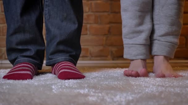 Nahaufnahme von nackten weiblichen und männlichen Beinen in Socken, die ihre Finger auf einem pelzigen Teppich vor gemauertem Hintergrund bewegen. — Stockvideo