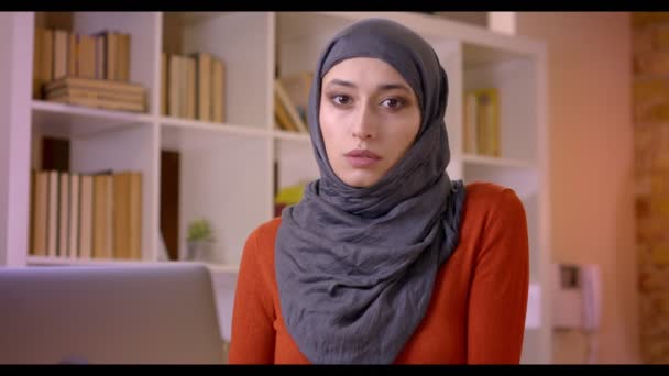 Primo piano di ripresa di giovane impiegata musulmana attraente digitando sul computer portatile guardando la fotocamera all'interno dell'ufficio — Video Stock