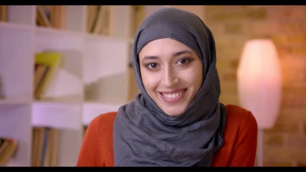 Closeup σουτ του νεαρός ελκυστική μουσουλμανική γυναίκα υπάλληλος βλέπουν φωτογραφική μηχανή και χαμογελαστός χαρούμενα στο χώρο εργασίας σε εσωτερικούς χώρους, στο γραφείο — Αρχείο Βίντεο