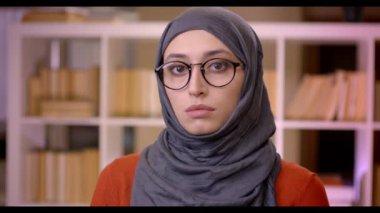 Closeup çekim genç çekici Müslüman başarılı kadın öğrencilerin Türban ve gözlük mutlu kapalı duran kütüphanede gülümseyen kamera bakıyor