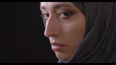 Portre yan arka plan üzerine siyah izole kamera için dönüm hijab genç çekici Müslüman kadın yüzü ateş görünümünde