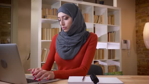 Vértes-lő a vonzó fiatal muzulmán üzletasszony, a hidzsáb dolgozik a laptop bent az irodában — Stock videók