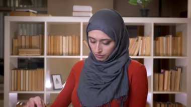 Closeup çekim genç çekici Müslüman kadın öğrencinin Tesettür kapalı kütüphanede kitap okuma