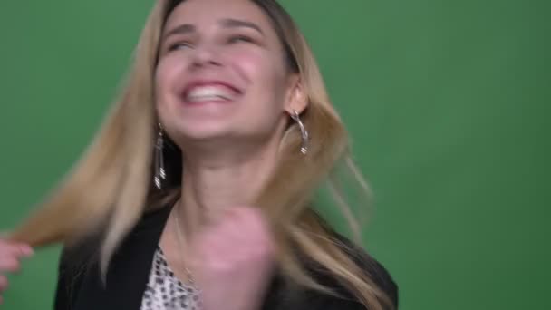 Closeup shoot of young attractive hipster caucasian female turning around with her hair fluttering laughing happily with background isolated on green — Stock Video