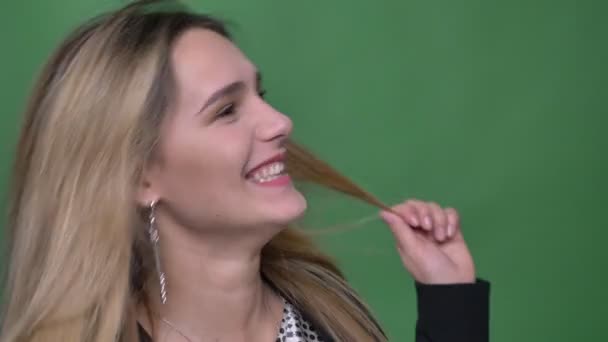 Closeup shoot of young attractive hipster caucasian female showing tongue and having fun while looking straight at camera with background isolated on green — Stock Video