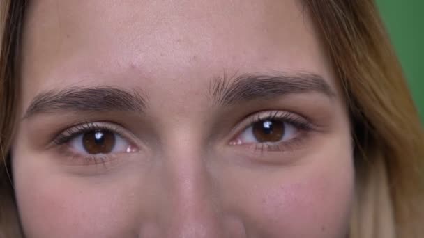 Closeup shoot of young attractive hipster caucasian female face with eyes being closed then looking straight at camera with smiling facial expression with background isolated on green — Stock Video