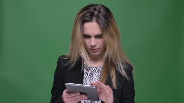 Крупним планом знімок молодого привабливого хіпстерського кавказького жіночого тексту на планшеті і дивитися на камеру з шокованим виразом обличчя з фоном ізольовані на зеленому — стокове відео