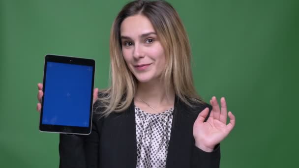 Tiro de perto de jovem atraente hipster caucasiano fêmea usando o tablet e mostrando tela azul para câmera com fundo isolado em verde — Vídeo de Stock
