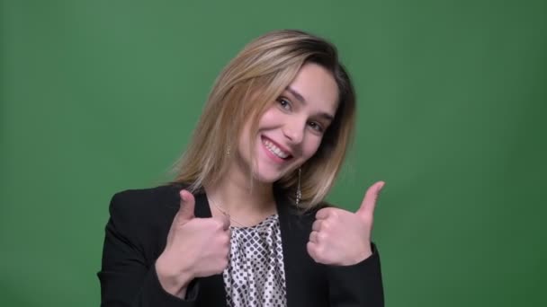 若い魅力的なヒップスターの白人女性のクローズアップ撮影親指を表示し、緑に分離された背景を持つカメラでまっすぐ見て笑顔 — ストック動画