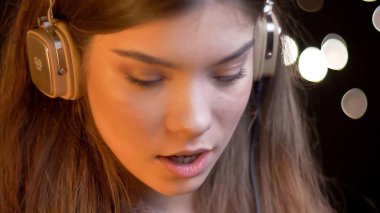 Genç çekici beyaz kadın zevk müzik kulaklık ile arka ışıkları bokeh portre portre