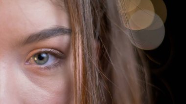 Closeup yarı-yüz bokeh arka plan ile doğrudan kameraya bakarak esmer saçlı genç çekici beyaz kadın portresi