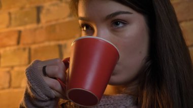 Closeup çekim genç çekici beyaz kadın rahat bir daire içinde kapalı bir fincan sıcak çay içme