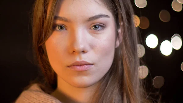 Retrato de close-up de jovem mulher caucasiana atraente com cabelo morena olhando diretamente para a câmera com fundo bokeh — Fotografia de Stock