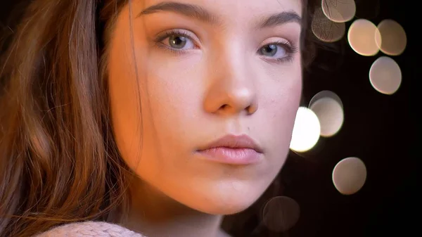 Close-up retrato de jovem muito caucasiano fêmea olhando em linha reta para a câmera pensativo com fundo bokeh — Fotografia de Stock