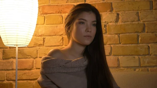 Close-up tiro de jovem mulher branca bonito assistindo uma TV com uma expressão facial curiosa em um aconchegante apartamento dentro de casa — Fotografia de Stock