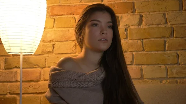 Closeup portrait of young pretty caucasian female watchimng a TV show with attentive facial expression in a cozy apartment Stock Image