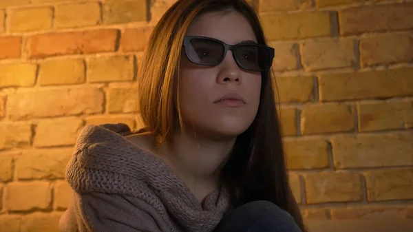 Nahaufnahme Porträt einer jungen attraktiven kaukasischen weiblichen Gesicht, das einen Film im Fernsehen in 3D-Brille mit neugieriger Mimik lizenzfreie Stockbilder
