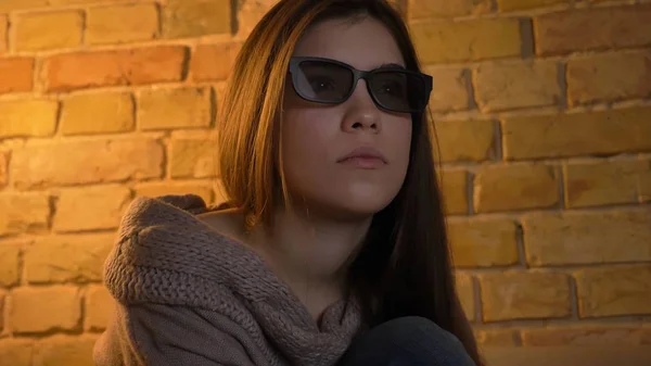 Primer plano retrato de joven atractiva cara femenina caucásica viendo una película en la televisión en gafas 3D con expresión facial curiosa Imágenes De Stock Sin Royalties Gratis