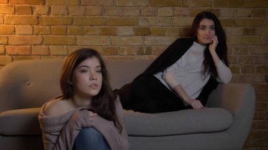Portre portre rahat bir daire içinde kapalı dinlenme sırasında merak yüz ifadesi ile Tv izlerken iki genç güzel kız