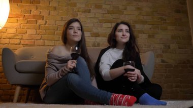 Tv izlerken ve şarap ile rahat bir daire kapalı yerde otururken soğutma iki genç güzel kadın portresi portre