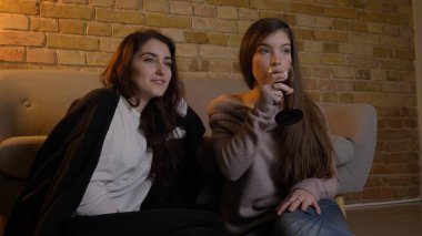 İki genç güzel kadın bir film Tv şarap ile rahat bir daire kapalı yerde oturan heyecan ile soğutma izlerken closeup portresi