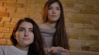 İki genç güzel kadın kapalı rahat bir daire içinde Tv izlerken portresi tabandan portre