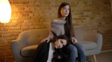 Portre yan görünüm portre iki genç güzel kadın bir film Tv oturma laidback rahat bir daire kapalı yerde izliyor. Bir kafa ile başka bir dizlerinin üzerine eğilerek