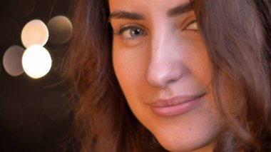 Closeup çekim kamera bokeh arka ışıkları ile düz bakarken cazibesi ile gülümseyen genç baştan çıkarıcı beyaz kadın