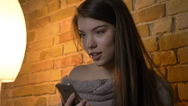 Close-up opnamen van jonge mooie Kaukasische vrouw met een casual gesprek op de telefoon tijdens het rusten op de Bank in een gezellig appartement binnenshuis — Stockfoto