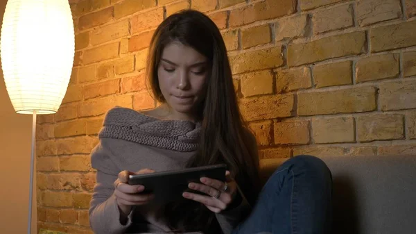Nahaufnahme Porträt einer jungen hübschen kaukasischen Frau, die auf dem Sofa in einer gemütlichen Wohnung sitzt und SMS schreibt — Stockfoto