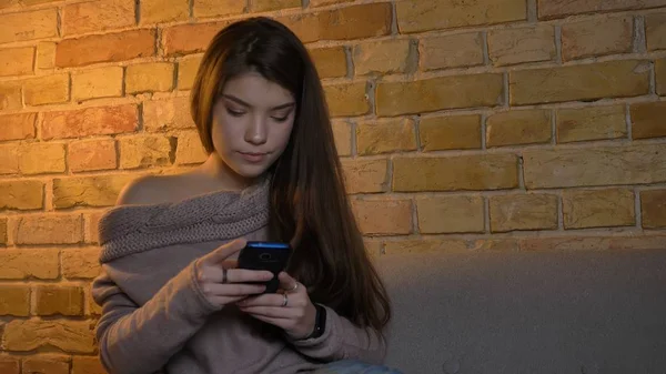 Nahaufnahme von jungen niedlichen kaukasischen weiblichen Nachrichten am Telefon beim Chillen in einer gemütlichen Wohnung drinnen — Stockfoto