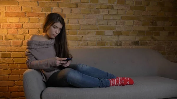 Nahaufnahme Shooting von jungen niedlichen kaukasischen weiblichen Nachrichten am Telefon, während sie sich entspannt auf dem Sofa zu Hause ausruhen — Stockfoto